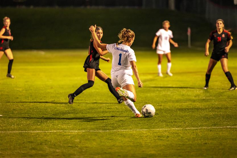 Soccer players dribble the ball down the field